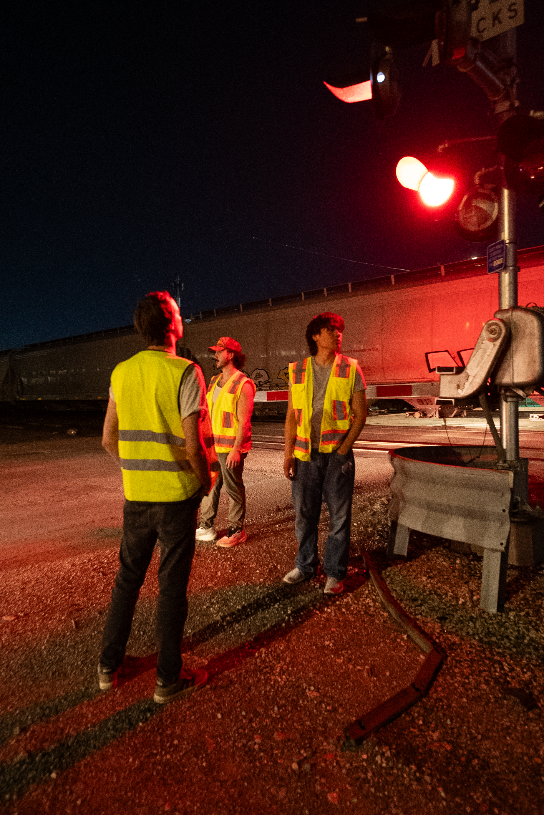 The Thrill of Speed cast standing at a railroad crossing under red lights