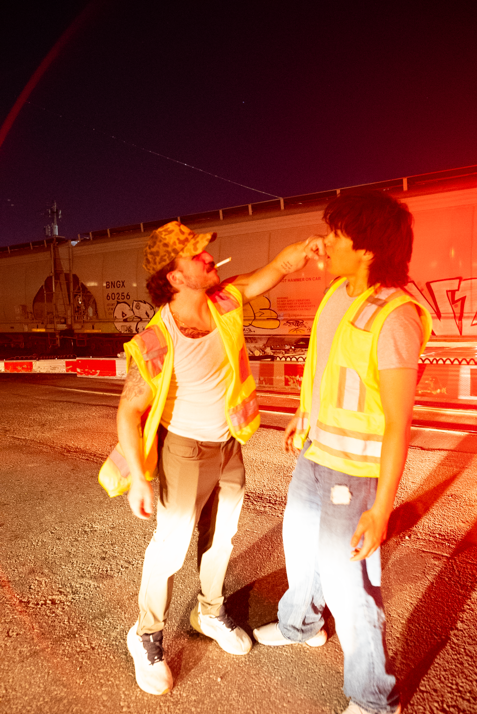 Two characters from The Thrill of Speed in safety vests beside a train at night