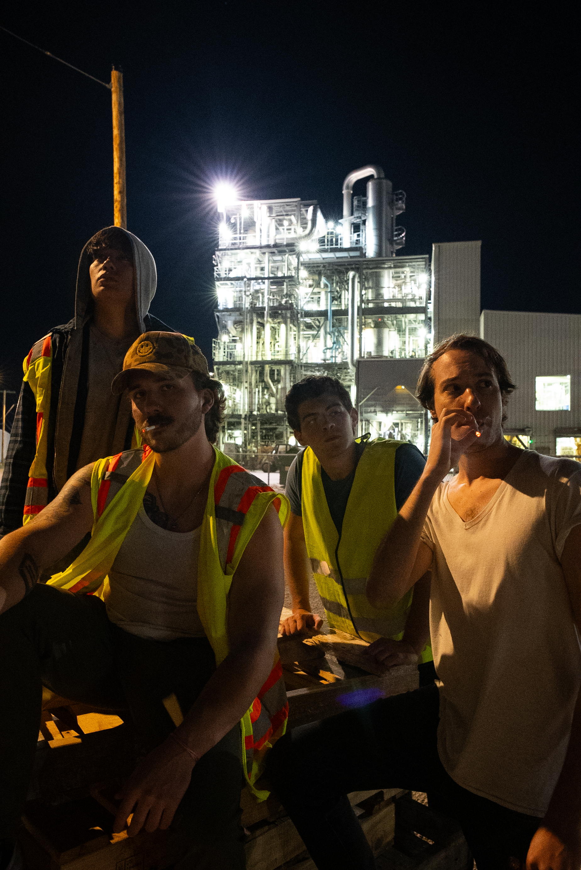 The Thrill of Speed cast seated in front of an industrial plant at night