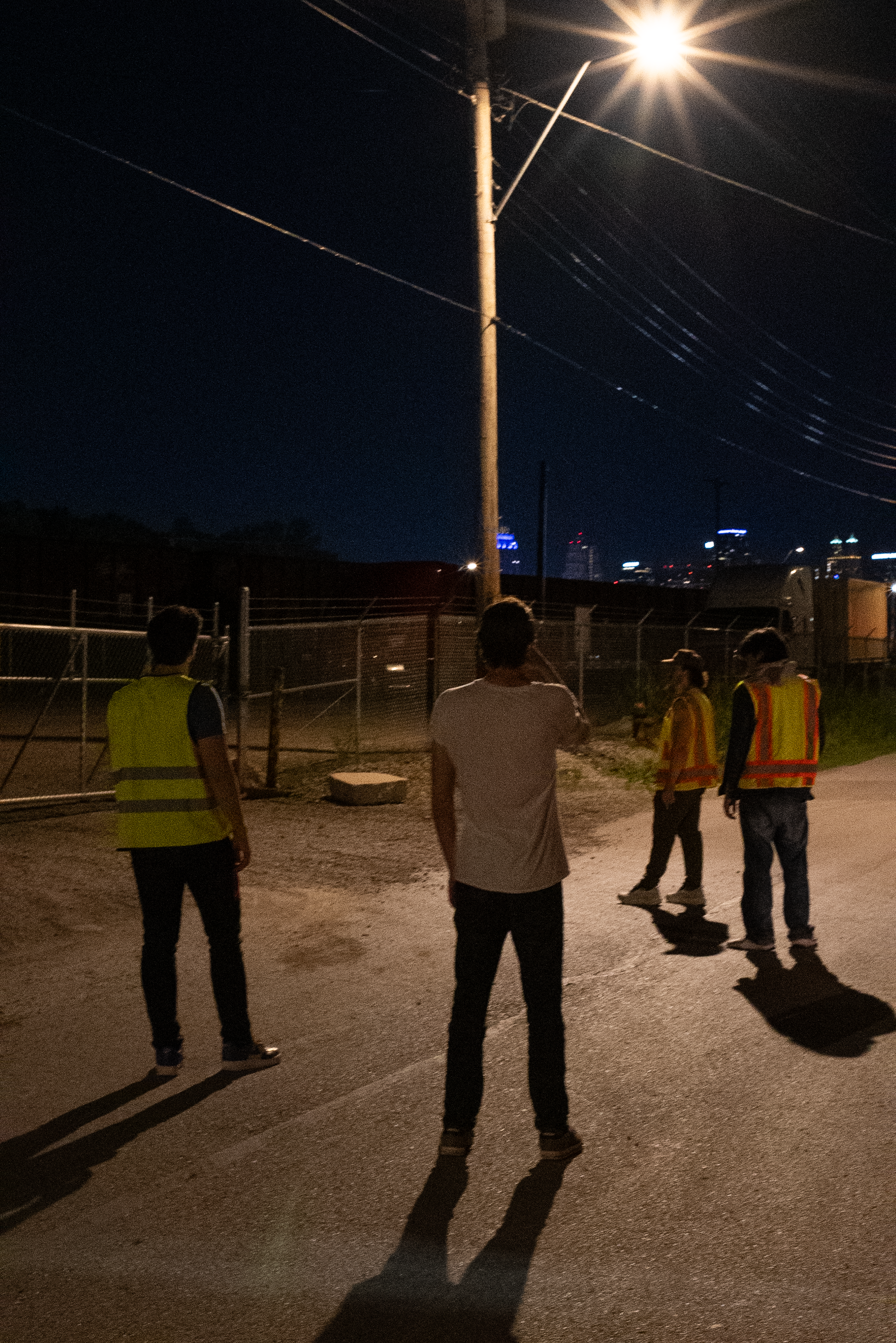 The Thrill of Speed cast standing in a road beneath a streetlight