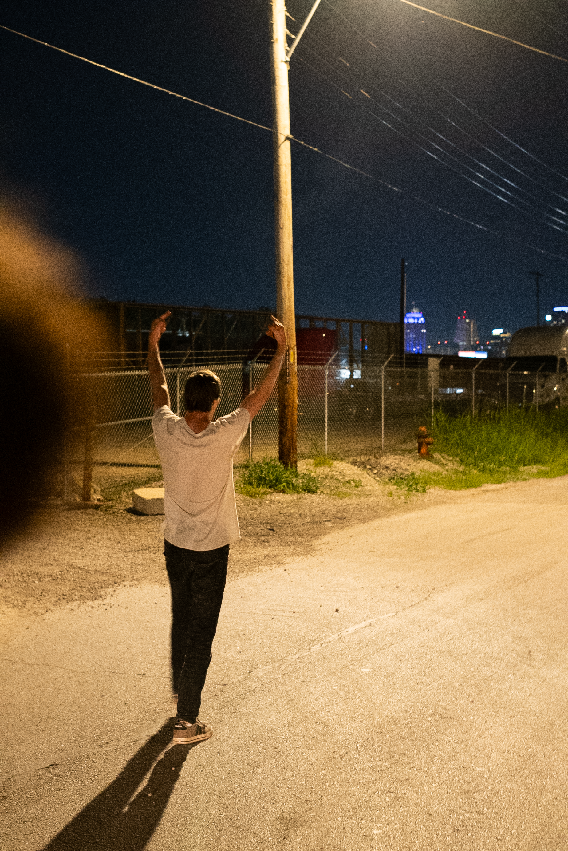 A character from The Thrill of Speed walking with arms raised under utility lines