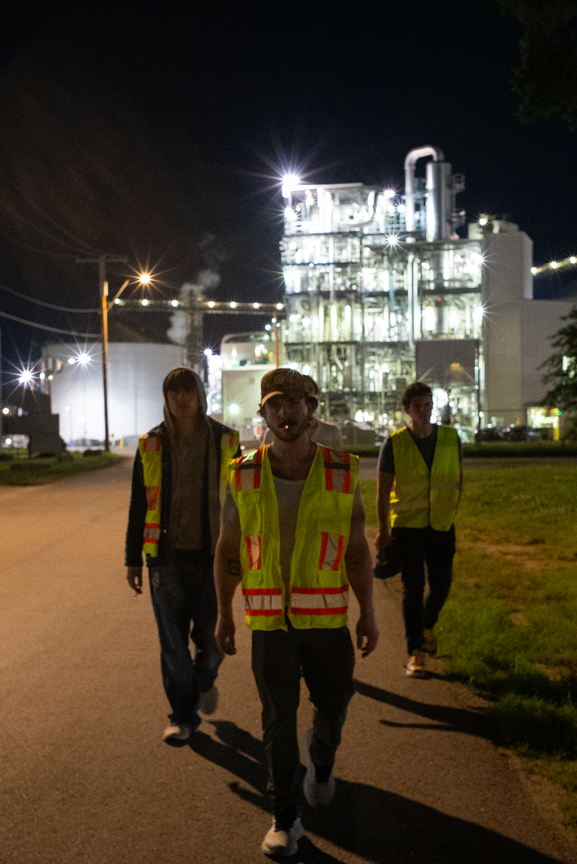 The Thrill of Speed cast walking toward camera outside an industrial plant at night